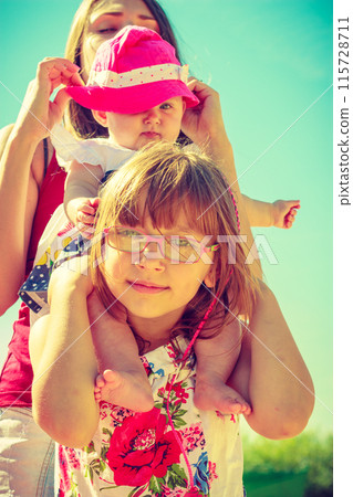 Toddler girl giving her little sister a piggyback 115728711