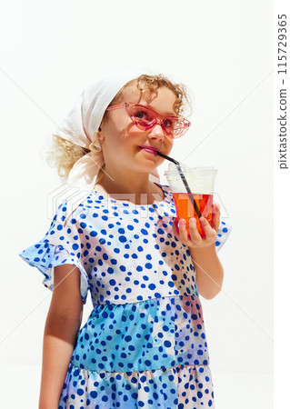 Young dreaming girl dressed summer dress drinking refreshing lemonade in hot summer day against white studio background. 115729365