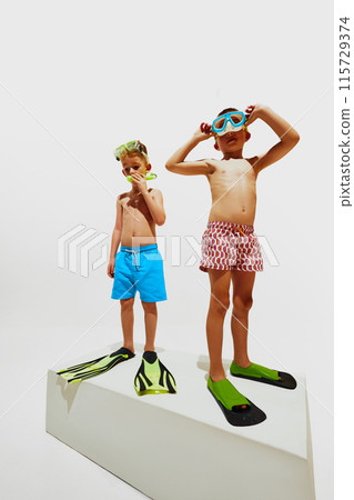 Cute little boys stand on white platform preparing to diving in hot summer day against white studio background. Cute little boys stand on white platform preparing to diving in hot summer day against white studio background. 115729374