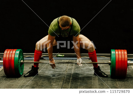 powerlift hold barbell with his hands, start attempt at deadlift competition 115729870