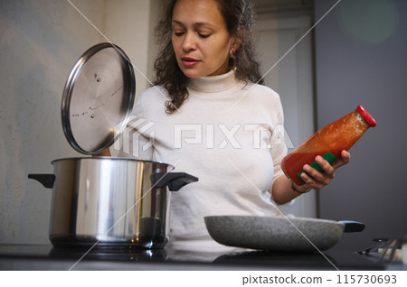 Woman cooking in kitchen with pot and tomato sauce Woman cooking in kitchen with pot and tomato sauce 115730693