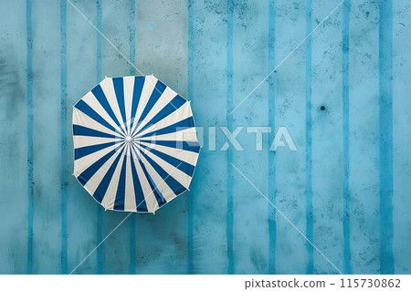 Aerial view of a swimming pool with a blue and white striped umbrella by the side, depicting a summer vacation concept. Minimalistic Aerial view of a swimming pool with a blue and white striped umbrella by the side, depicting a summer vacation concept. Minimalistic 115730862