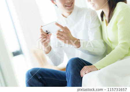 A couple looking at a smartphone 115731657