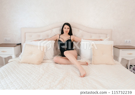 Woman in Black Bodysuit Sitting on Bed in Bedroom 115732239