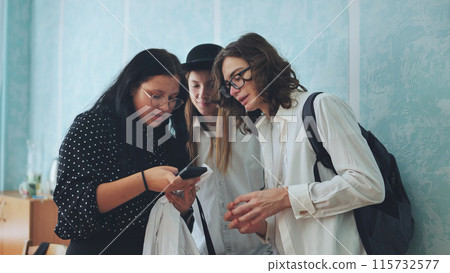 Three high school students discussing something on a smartphone. Three high school students discussing something on a smartphone. 115732577
