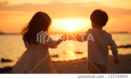 Back view of a little boy and girl holding hands on a sandy beach with the sunset in the background Back view of a little boy and girl holding hands on a sandy beach with the sunset in the background 115734945