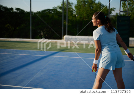 Female tennis player preparing to serve on outdoor court 115737595