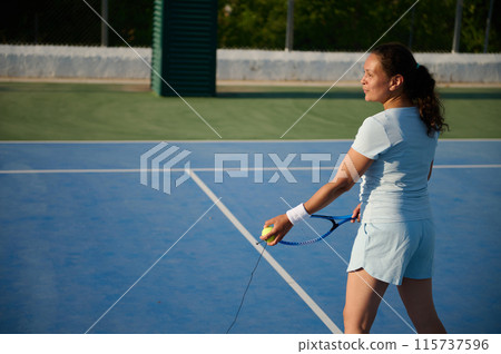 Female tennis player preparing to serve on outdoor court 115737596