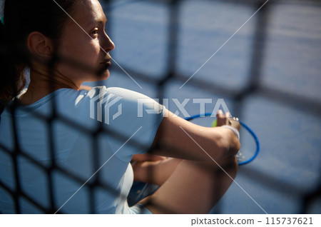 Woman sitting on tennis court with racket and tennis ball 115737621