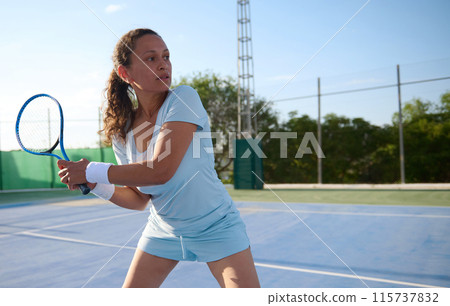 Focused woman playing tennis on an outdoor court Focused woman playing tennis on an outdoor court 115737832