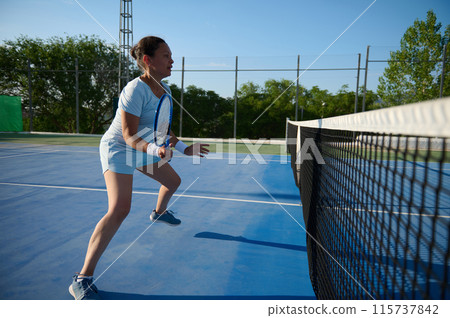 Female tennis player ready to hit the ball on outdoor court Female tennis player ready to hit the ball on outdoor court 115737842