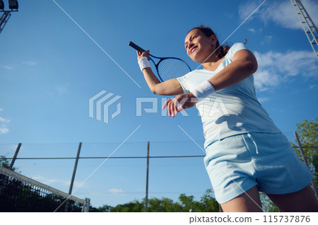 Woman playing tennis on outdoor court under blue sky 115737876