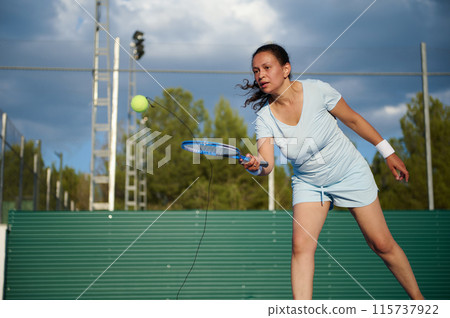 Woman playing pickleball outdoors on a sunny day 115737922