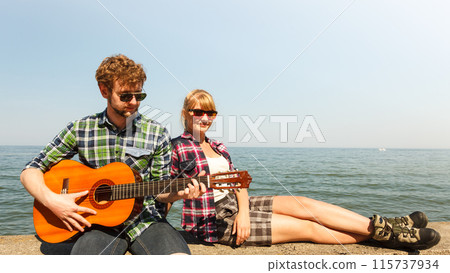 Young man hipster playing guitar for woman. Young man hipster playing guitar for woman. 115737934