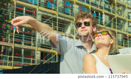 Couple on front of new house with blueprint project Couple on front of new house with blueprint project 115737945