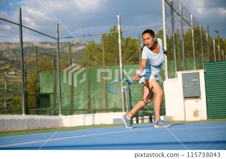 Young woman playing tennis on a sunny outdoor court 115738043