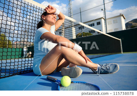 Tired woman resting on tennis court after intense practice 115738078
