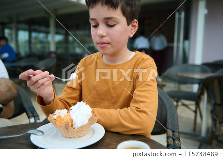Boy enjoying a waffle ice cream at an outdoor cafe 115738489