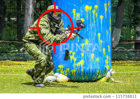 Aiming on paintball sport player in protective uniform and mask playing with gun outdoors Aiming on paintball sport player in protective uniform and mask playing with gun outdoors 115738811