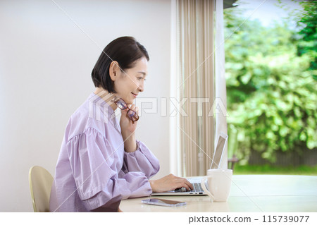 中間女性觀看個人計算機在客廳 115739077