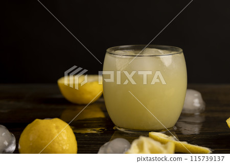 ripe sliced lemon and cold juice with ice and their reflection on a wet table 115739137
