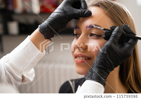 A woman receives a brow lamination procedure from a professional A woman receives a brow lamination procedure from a professional 115739398