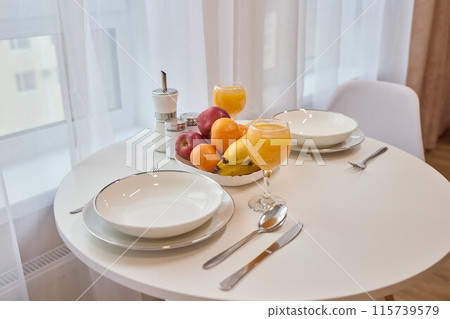 Table set with dishware, fruit bowl, and utensils for a meal 115739579