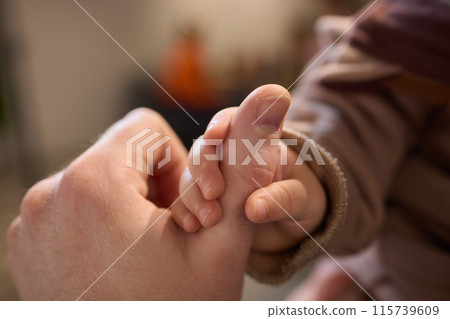A close up of a persons thumb touching a baby tiny finger 115739609