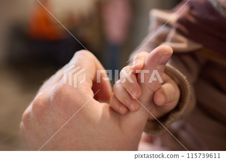 A close up of a persons thumb touching a baby tiny finger 115739611