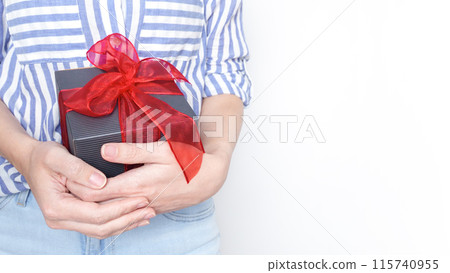 Young woman holding a black gift box with a red ribbon in her hands. Isolated on white background. 115740955