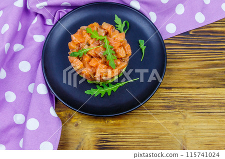 Salmon tartare with avocado and arugula on wooden table. Top view Salmon tartare with avocado and arugula on wooden table. Top view 115741024