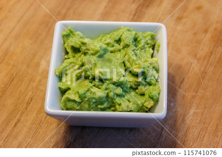 Bowl of guacamole on a wooden table 115741076