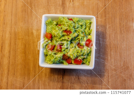 Bowl of guacamole on a wooden table 115741077