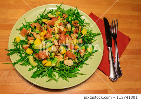 Fresh healthy salad with mango, avocado, salmon, arugula and croutons on wooden table Fresh healthy salad with mango, avocado, salmon, arugula and croutons on wooden table 115741091