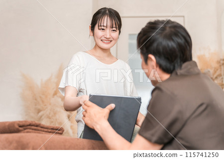 A woman receiving counseling at a chiropractic clinic/osteopathic clinic/massage and a chiropractor/therapist (tablet PC) 115741250