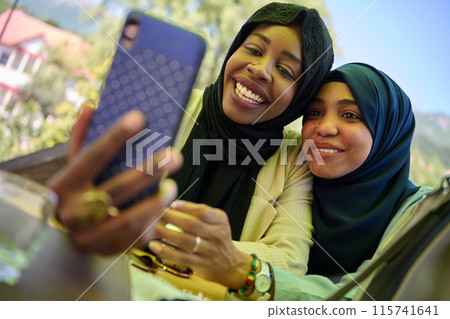 Middle Eastern Muslim Women Capturing Selfies in Serene Surroundings 115741641