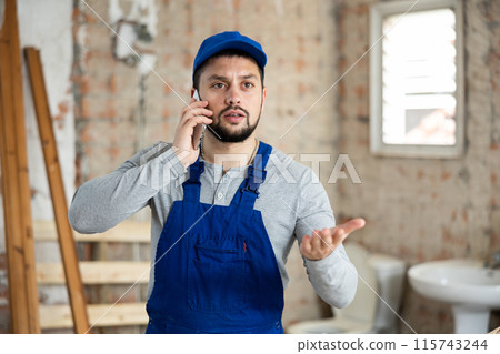 Builder talking on phone at construction site 115743244