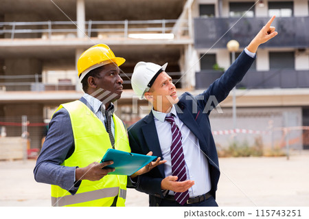 Young architect discusses a construction plan with an engineer Young architect discusses a construction plan with an engineer 115743251