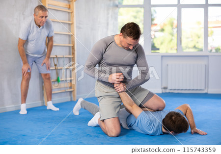 Adult and young men training self-defense techniques Adult and young men training self-defense techniques 115743359