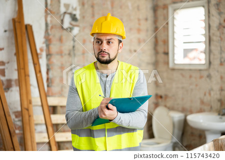 Qualified builder writes notes on a tablet Qualified builder writes notes on a tablet 115743420