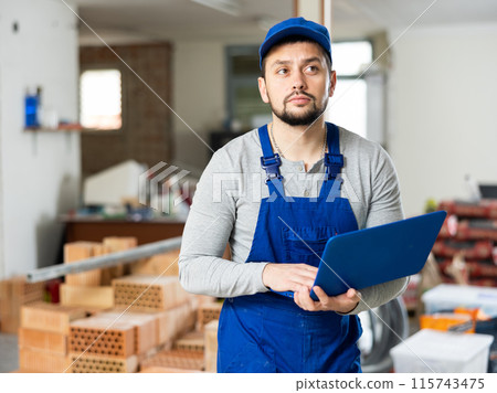Builder handyman checking plan of house renovation on laptop 115743475