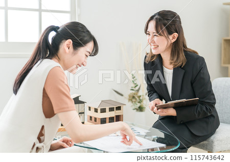 An Asian woman consulting with a businesswoman who explains and sells home ownership, real estate, renovations, and asset management 115743642