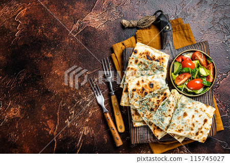 Freshly baked Turkish Gozleme, flatbread with greens and cheese. Dark background. Top view. Copy space Freshly baked Turkish Gozleme, flatbread with greens and cheese. Dark background. Top view. Copy space 115745027