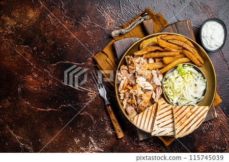Turkish Doner kebab or gyros on a plate with french fries, vegetables and salad. Dark background. Top view. Copy space Turkish Doner kebab or gyros on a plate with french fries, vegetables and salad. Dark background. Top view. Copy space 115745039