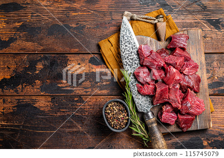 Sliced Raw venison dear meat for a stew, game meat on butcher cutting board. Wooden background. Top view. Copy space 115745079