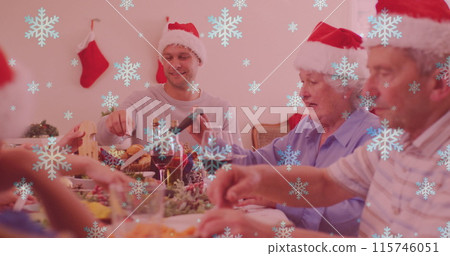 Image of snow falling over smiling caucasian family with santa hats having dinner 115746051