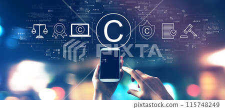 Copyright concept with a smartphone in city lights at night Copyright concept with a smartphone in city lights at night 115748249