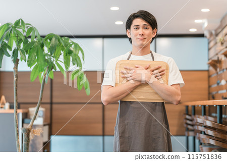 A young Asian man working at a cafe with a sad expression, troubled by customer harassment A young Asian man working at a cafe with a sad expression, troubled by customer harassment 115751836