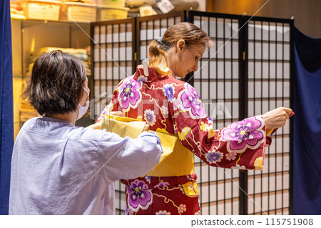 Foreign female tourists getting dressed in kimonos at a kimono rental shop Foreign female tourists getting dressed in kimonos at a kimono rental shop 115751908