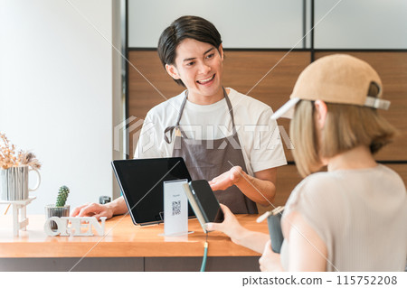 A cafe clerk who accepts electronic payments and smartphone payments at the cafe cash register and checkout. 115752208